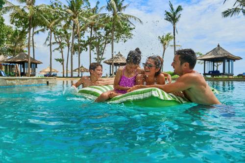 un grupo de personas sentadas en el agua en un resort en Conrad Bali en Nusa Dua