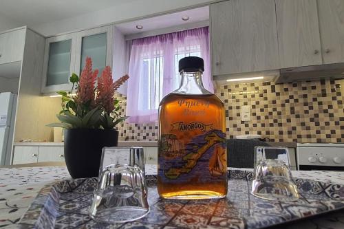 una botella de whisky sentada en una mesa con dos vasos en Larinaki's Cozy Apartment No1, en Órmos Aiyialís