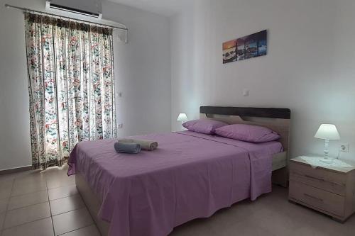 1 dormitorio con 1 cama morada y 2 almohadas en Larinaki's Cozy Apartment No1, en Órmos Aiyialís