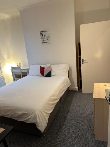 a bedroom with a bed with white sheets and pillows at Suite double room in Tottenham. in London