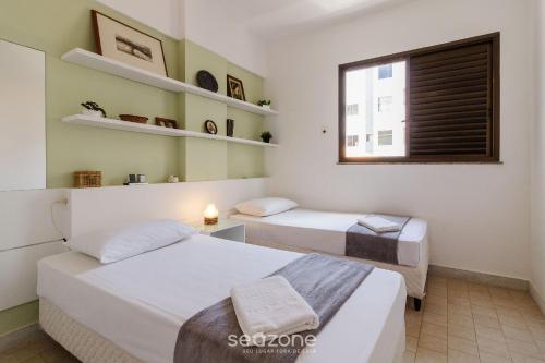 - 2 lits dans une petite chambre avec fenêtre dans l'établissement Aconchegante apartamento próx da praia BFC204, à Cabo Frio