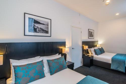 ein Hotelzimmer mit einem Bett und einem Bett und einem Bett sidx sidx sidx sidx sidx in der Unterkunft Gilmer Apartment Hotel in Wellington