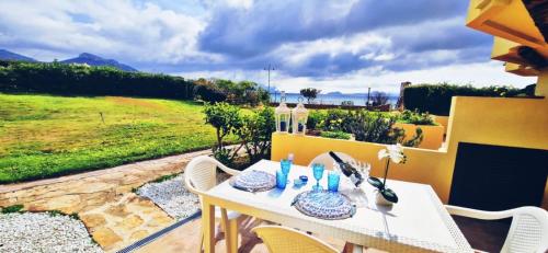 une table et des chaises blanches avec vue sur un champ dans l'établissement Appartamenti delfini terza spiaggia, à Golfo Aranci