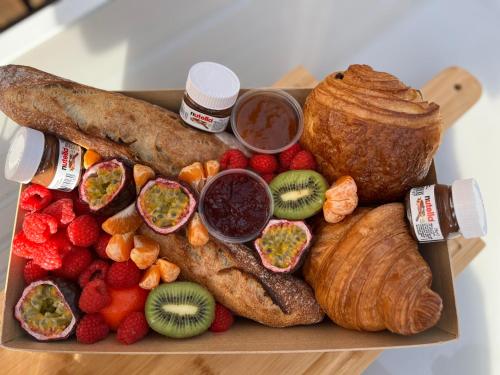 uma bandeja de alimentos com diferentes tipos de pão e frutas em Loft indépendant Proche Paris em Villebon-sur-Yvette