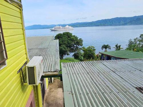 a yellow building with a cruise ship in the water at Limericks by the Sea in Savusavu