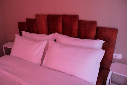 a bed with a red head board with pink pillows at Sunny Home overlooking Tirana in Tirana
