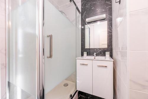 a white bathroom with a sink and a shower at Cosy Appart Paris- la Défense in Courbevoie