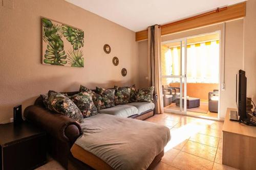 een woonkamer met een bank en een televisie bij Apartamento familiar centrico in Denia