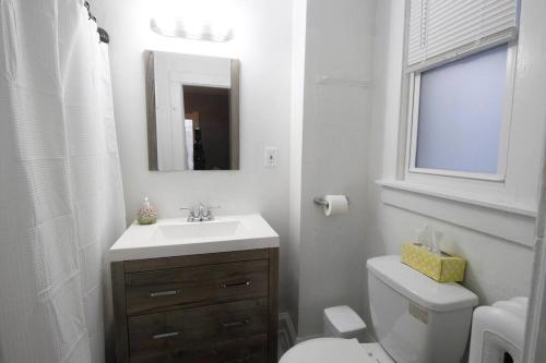 a bathroom with a sink and a toilet and a mirror at Renovated Brady St. Classic in Milwaukee