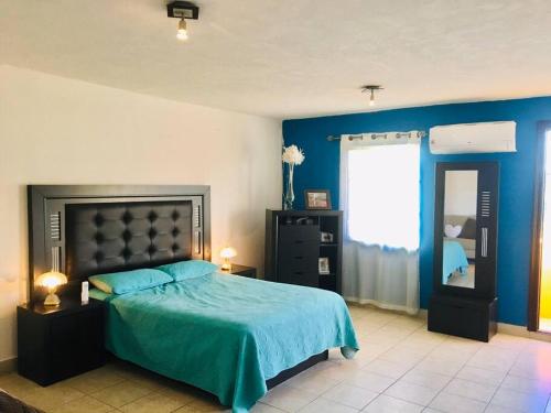 a bedroom with a bed and a blue wall at CASA ENTERA CERCA DE PRINCIPALES VIAS EN TIJUANA in Tijuana