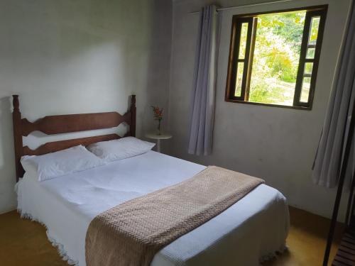 um quarto com uma cama branca e uma janela em Sítio Recanto Amado. em Santa Teresa