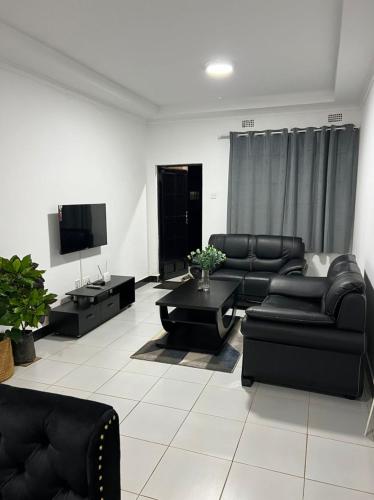 a living room with black furniture and a flat screen tv at Queen City Homes in Lilongwe