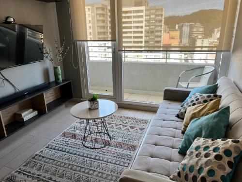 ein Wohnzimmer mit einem Sofa und einem Tisch in der Unterkunft Apartamentos Concepción Centro in Concepción