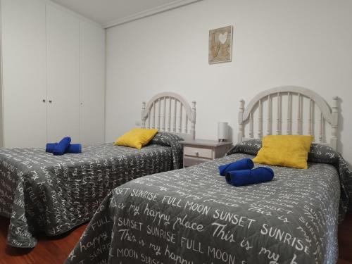 twee bedden met blauwe kussens in een kamer bij BURGOS CONTEMPLA Centro histórico. Frente al arco in Burgos