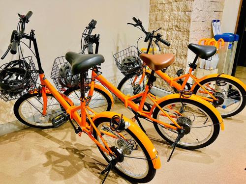 three orange bikes are parked next to each other at Hotel Taiyo Nouen Furumitsu in Matsuyama