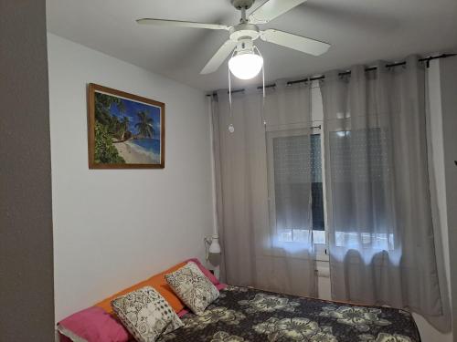 een woonkamer met een plafondventilator en een raam bij NOVA PINEDA PORT AVENTURA in La Pineda