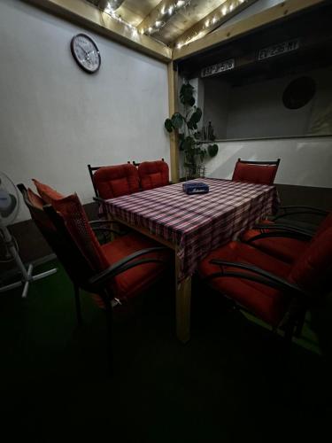 a dining room table with chairs and a clock on the wall at Guest House Nana in Mostar