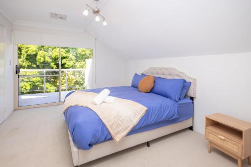 a bedroom with a bed with blue sheets and a window at Urban Retreat Townhouse near CBD in Perth