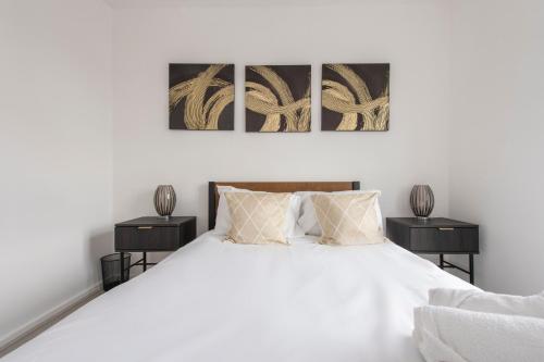 een slaapkamer met een wit bed en 2 nachtkastjes bij Modern Luxury Apartment by Bow Road Station in Londen