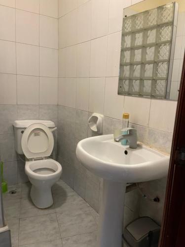 a white bathroom with a toilet and a sink at Sandy Shores-Nyali, Mombasa in Mombasa
