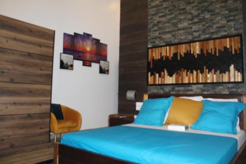 a bedroom with a blue bed with a brick wall at Libdo Immos in Cotonou