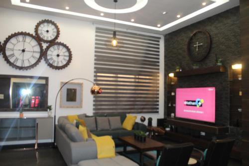 a living room with a couch and a tv and clocks at Libdo Immos in Cotonou