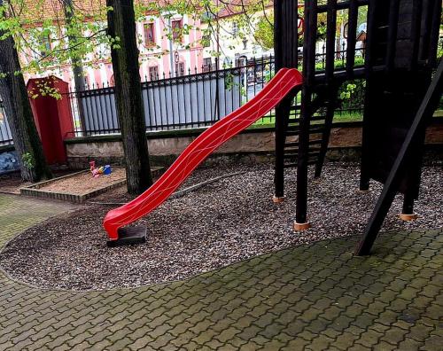 a red slide on a playground in a park at Penzion Nové dvory in Kutná Hora