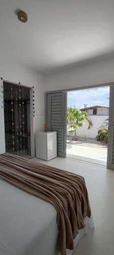 a white bedroom with a bed and a large window at Pontal Praia Suítes in Fortim