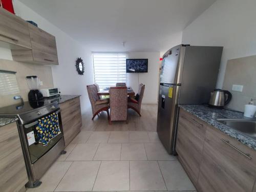 a kitchen with a stainless steel refrigerator and a table at Casa El Rincón del Sol in Quito