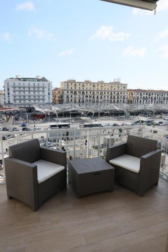 two chairs and tables on a balcony with a parking lot at Napoli Central Suites in Naples