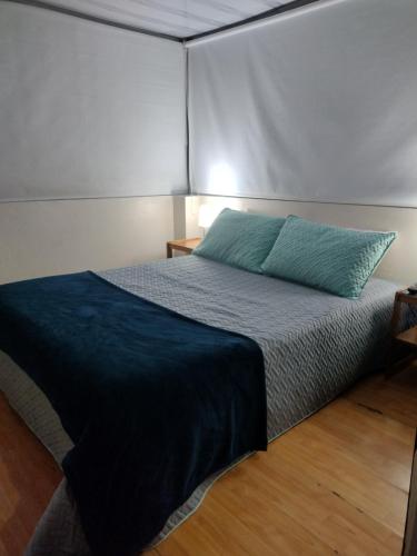 a bedroom with a bed with a blue pillow on it at Natural Getaway in Bogotá