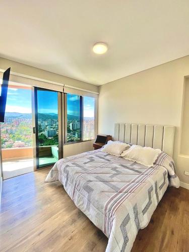 a bedroom with a large bed and a large window at Lujo & Vista soñada en Cocha in Cochabamba