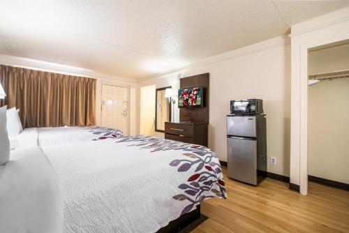 a hotel room with a bed and a refrigerator at Red Roof Inn North Dallas - Park Central in Dallas
