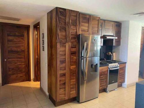 a kitchen with a stainless steel refrigerator and wooden cabinets at Bello departamento con vista al mar in Puerto Vallarta