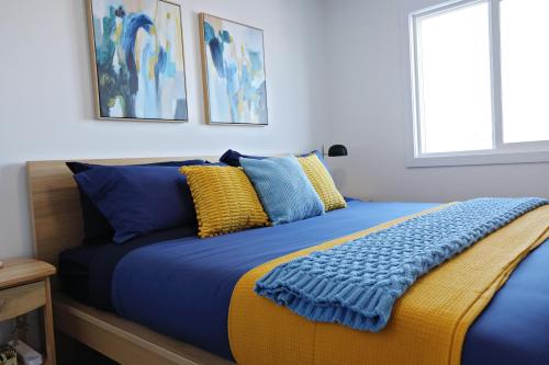 a bedroom with a bed with blue and yellow pillows at BoHo Retreat with King Beds, Golf, Disney+, Near WEM in Edmonton