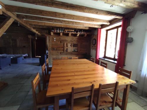 une grande table en bois dans une pièce avec des chaises dans l'établissement Maison 10 personnes vue montagne, à Vallouise
