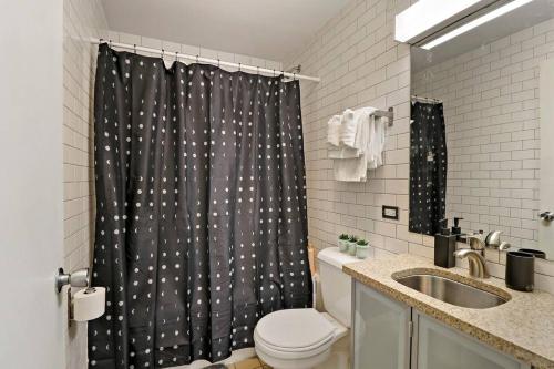 a bathroom with a shower curtain with a toilet and a sink at Inviting 2-Bedroom Apt in Hyde Park - The Blackwood 0404 in Chicago