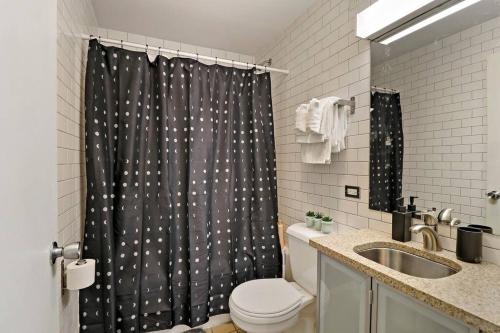 a bathroom with a shower curtain with a toilet and a sink at Inviting 2-Bedroom Apt in Hyde Park - The Blackwood rep in Chicago