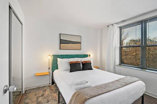 a bedroom with a large white bed with a window at Inviting 2-Bedroom Apt in Hyde Park - The Blackwood 0404 in Chicago