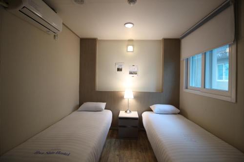 Duas camas num pequeno quarto com uma janela em Dongdaemun Hwashin Hostel em Seul