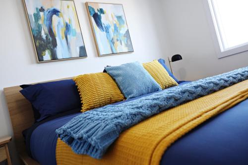 a bed with a blue blanket and pillows on it at BoHo Retreat with King Beds, Golf, Disney+, Near WEM in Edmonton