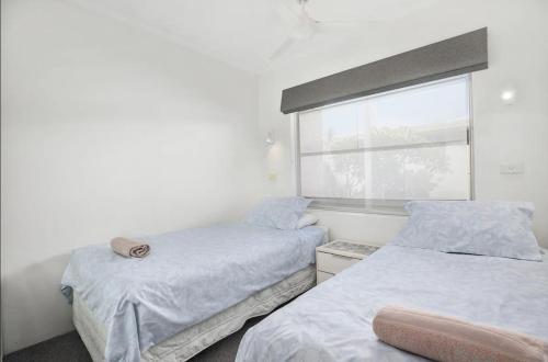 two beds in a room with a window at Sand and Sea 1 - Opposite Sawtell's Main Beach & Steps to Cafes, Restaurants & Boutiques! in Sawtell