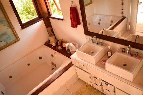 La salle de bains est pourvue de 2 lavabos, d'une baignoire et d'un miroir. dans l'établissement Casa Kubo, à Itacaré