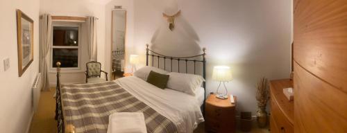 een slaapkamer met een bed met witte lakens en groene kussens bij Park side Cottage, Number 2, The Morays in Blackford