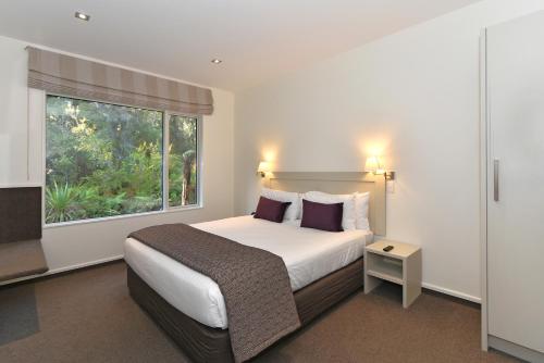 a hotel room with a bed and a window at Aspen Court Franz Josef in Franz Josef