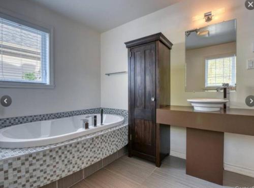 een grote badkamer met een bad en een wastafel bij Magnifique maison près de l’eau in Laval