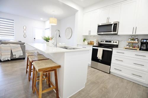 a kitchen with white cabinets and a stove top oven at BoHo Retreat with King Beds, Golf, Disney+, Near WEM in Edmonton