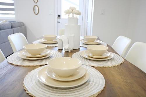 a wooden table with white bowls and plates on it at BoHo Retreat with King Beds, Golf, Disney+, Near WEM in Edmonton