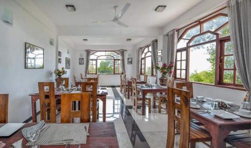 un comedor con mesas, sillas y ventanas en The Richmond House Kandy en Kandy