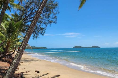 a beach with two palm trees and the ocean at Serene 2BR Beachfront Getaway on the Esplanade in Clifton Beach